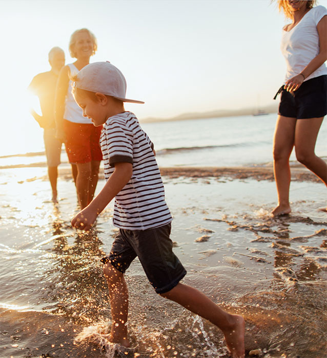 Young boy with family playing in the shore water