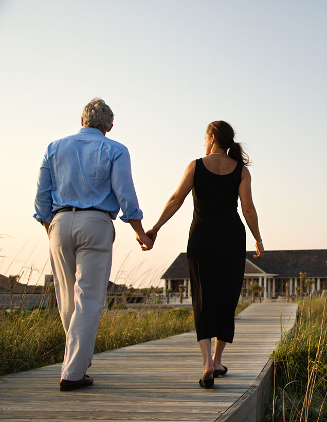 Couple holding hands walking on beach boardwalk